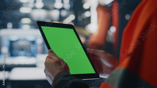 Specialist hands holding green screen tablet at manufacturing facility close up.