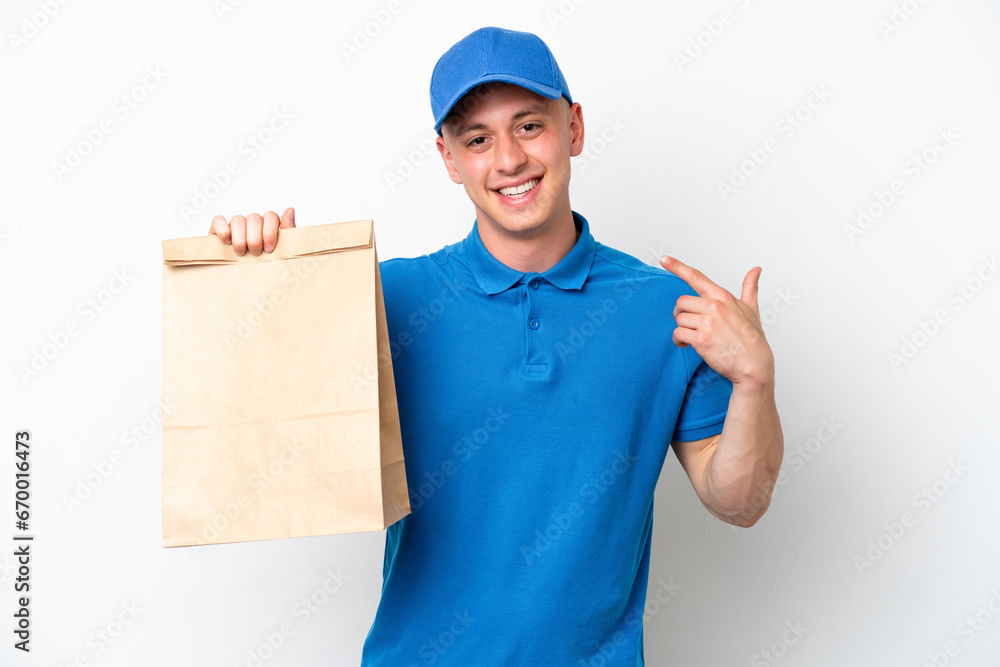 Young Brazilian man taking a bag of takeaway food isolated on white background giving a thumbs up gesture Young Brazilian man taking a bag of takeaway food isolated on white background giving a thumbs up gesture