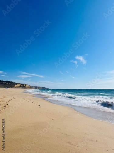 Ocean bay, rocky ocean coast, sandy beach, blue sky