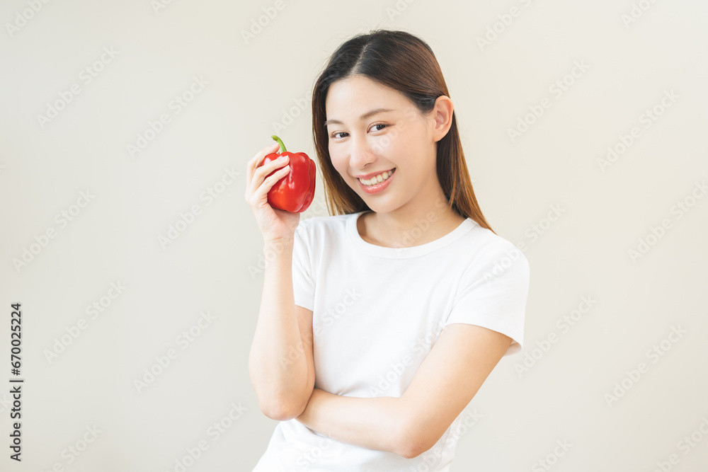 Healthy diet food with capsicum, portrait smile of asian young woman holding, eating red bell pepper isolated on background, fresh vegetable from nature organic for wellness, happy nutrition lifestyle Healthy diet food with capsicum, portrait smile of asian young woman holding, eating red bell pepper isolated on background, fresh vegetable from nature organic for wellness, happy nutrition lifestyle