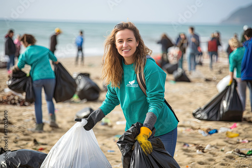volunteer smiling looking at a camera picking up a plastic litter on a beach © Kien