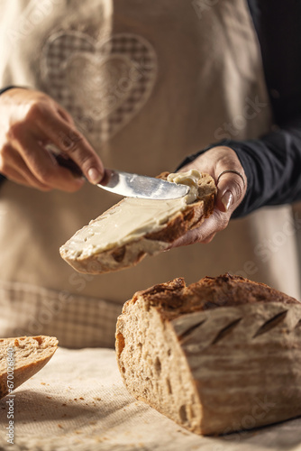 A woman makes delicious bread, spreads cream cheese with a cutlery knife - Close up. Woman hands spreading cream cheese on bread slice.