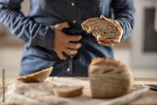 Woman can't eat bread and grain products because of gluten intolerance. A young celiac woman suffers from abdominal pain after eating fresh bread photo