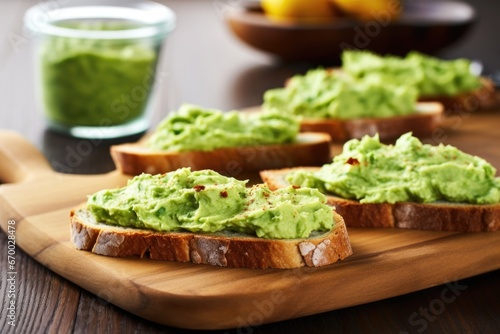 avocado spread on toasted baguette slices on a wooden board