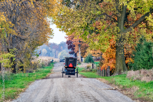 An Amish buggy on a rural road in Autumn with fall colors.