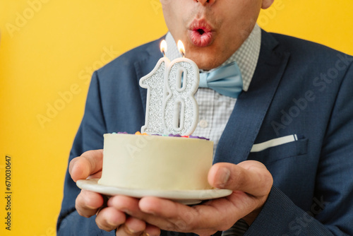Man blowing 18th birthday candle on cake photo