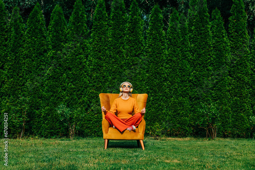 Blond woman sitting and meditating on chair in garden photo