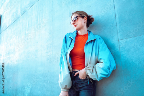 Woman wearing jacket leaning on blue wall photo