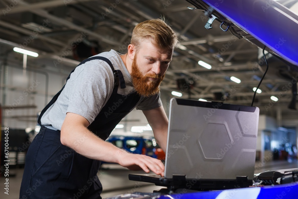A man is a mechanical engineer during troubleshooting in a car with the help of professional equipment at a service station A man is a mechanical engineer during troubleshooting in a car with the help of professional equipment at a service station