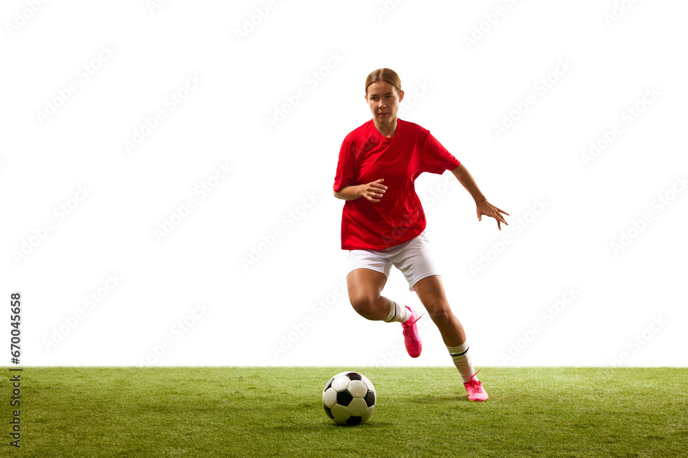 Ball dribbling. Young woman, female football player in motion during game, training on green grass isolated on white background. Concept of sport, competition, action, success. Copy space for ad Ball dribbling. Young woman, female football player in motion during game, training on green grass isolated on white background. Concept of sport, competition, action, success. Copy space for ad