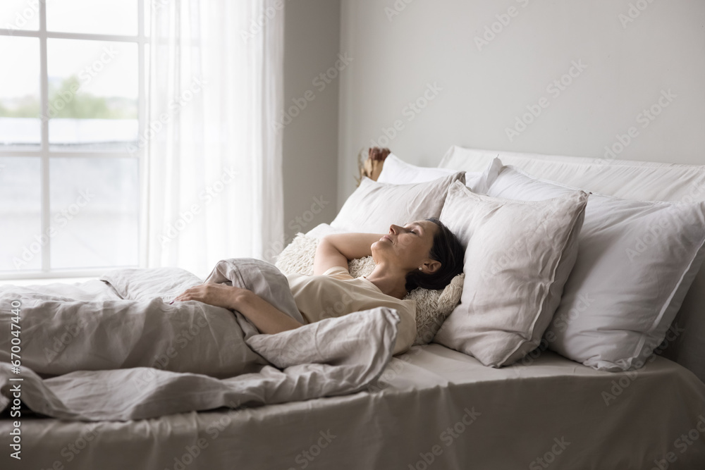 Older woman sleeping alone in double bed in modern, light bedroom, looks serene while resting in early morning at home, enjoy comfortable orthopaedic mattress and fresh beddings, having healthy sleep Older woman sleeping alone in double bed in modern, light bedroom, looks serene while resting in early morning at home, enjoy comfortable orthopaedic mattress and fresh beddings, having healthy sleep