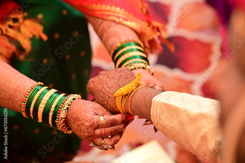 Indian bride Tie a Turmeric Thread Yellow knot on hand of groom. Close Up Hands of bride and Groom in hindu wedding. Marathi Wedding Ceremony. Maharashtra Culture. Hindu wedding rituals and ceremony. 