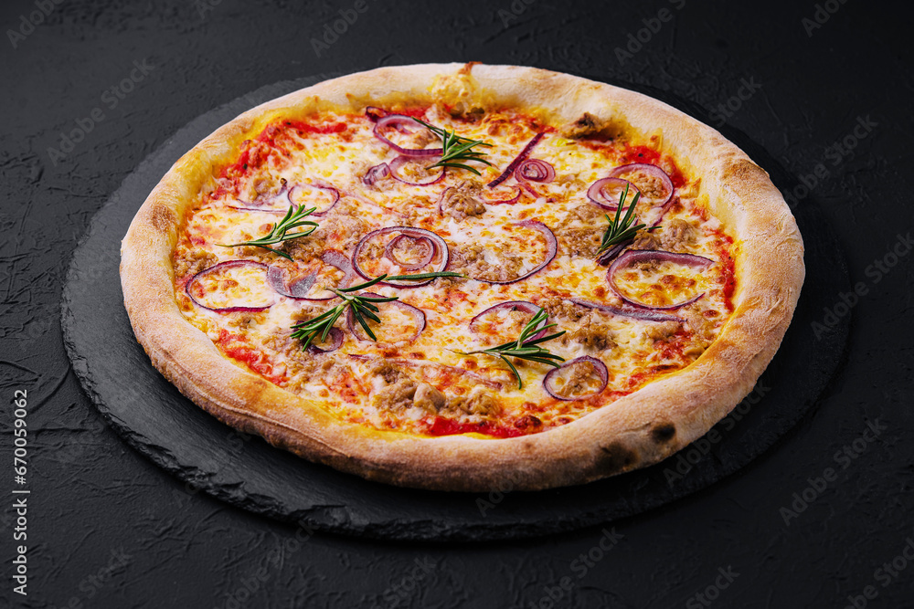 Pizza with tuna and red onion on stone cutting board