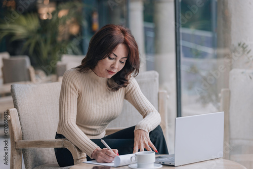 Elegant woman typing in front of a computer over coffee.