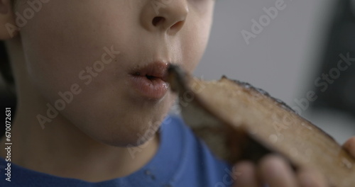 One small boy taking a bite of toast bread, close-up child mouth eating carb food in speed ramp