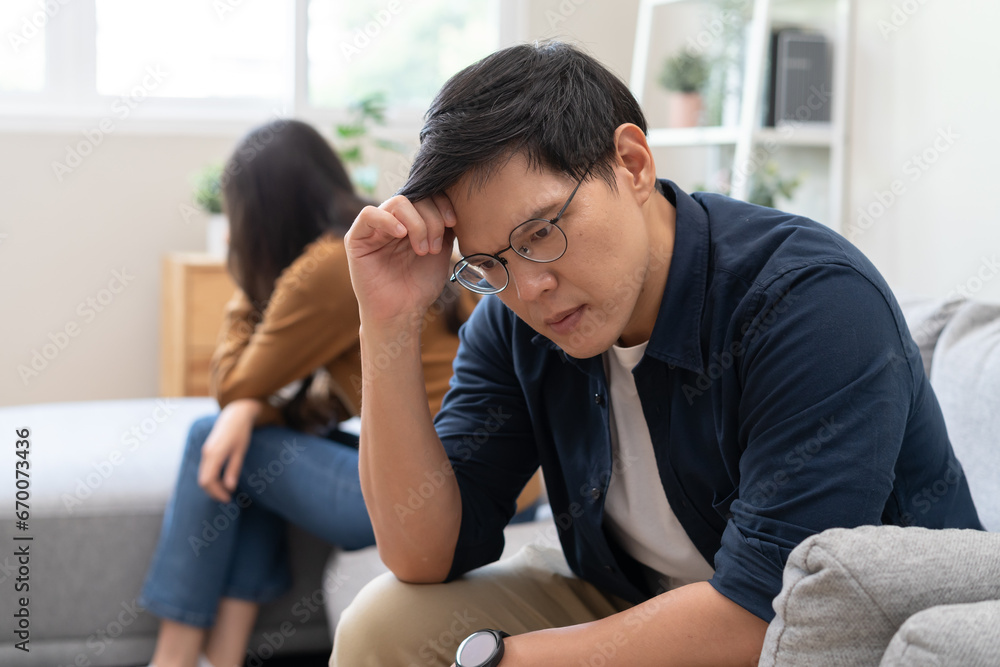 Family problem concept, Asian wife and husband sitting back to back in the living room at home have problems in a relationship and have an argument Family problem concept, Asian wife and husband sitting back to back in the living room at home have problems in a relationship and have an argument