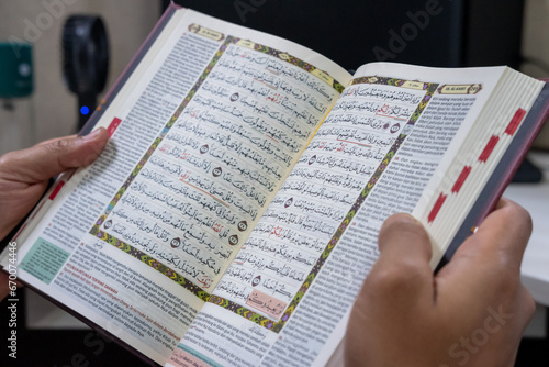 Hand of asian moslem man holding the Holy Koran. Selective focus.