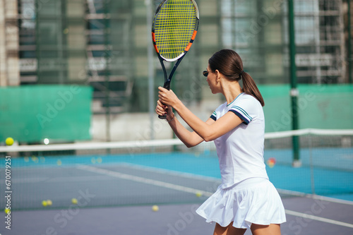 photo of a female tennis player from the back in training, playing tennis on the court.