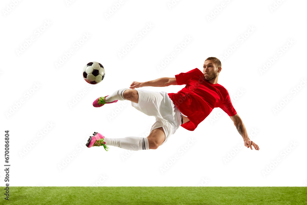 Portrait of young Caucasian soccer football player looks confident practicing kicking ball in motion against white background on green grass.
