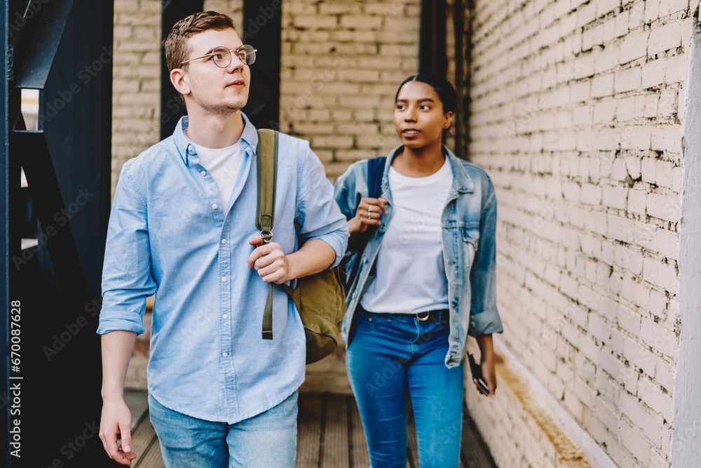 teenagers in casual wear strolling with backpacks hipster guy in eyewear looking up teenagers in casual wear strolling with backpacks hipster guy in eyewear looking up