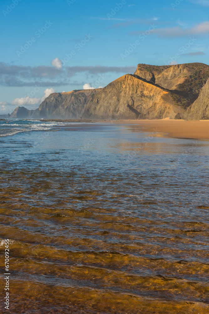 Cordoama Beach in Algarve Portugal, with sandy shore, dramatic cliffs and waves on Atlantic Ocean