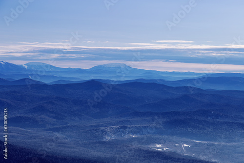 Winter nature panorama of far away blue mountains, picturesque view, aerial tonal perspective, monochrome photo of range mountains and blue sky, hills covered forest, great landscape in Altai © yrabota
