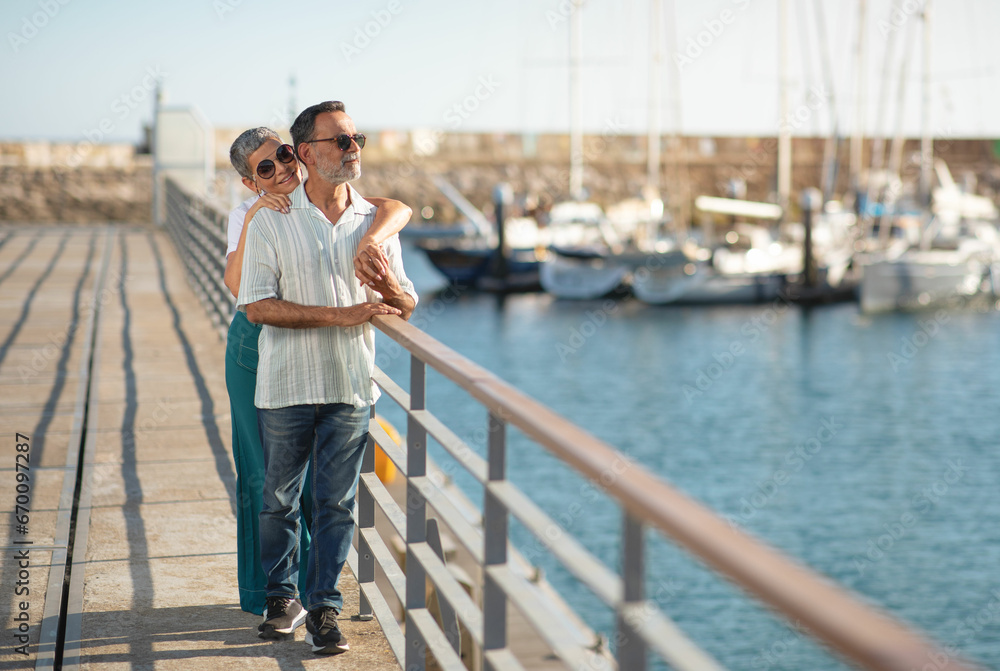 Mature spouses enjoying embrace near ships and yachts at marina Mature spouses enjoying embrace near ships and yachts at marina
