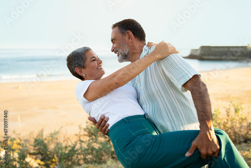 Mature husband and wife hugs engaging dancing during seaside getaway