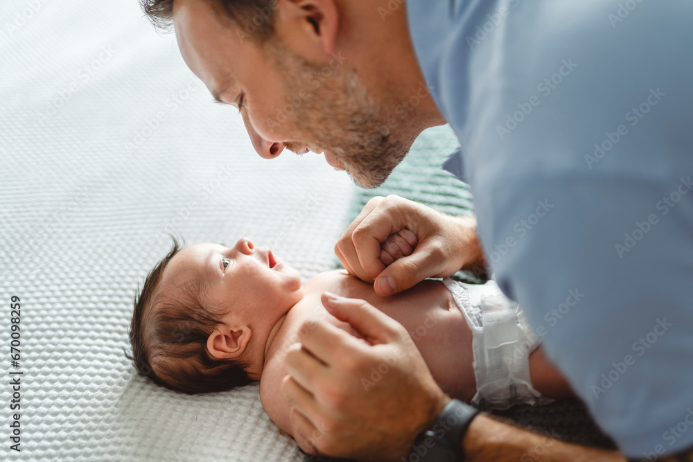father on bedroom with his newborn baby son father on bedroom with his newborn baby son