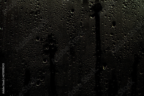 Wet window with water streaks. Glass with raindrops on a dark background. Background or overlay for use in design.