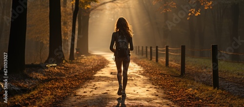 A woman runs on a trail on a sunny morning on a forest road. against the direction of sunlight photo