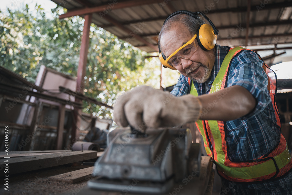 An elderly carpenter works the wood with meticulous care. An elderly carpenter works the wood with meticulous care.
