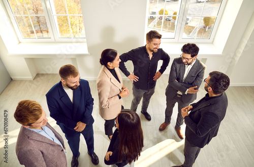 Different people meeting and communicating at a modern business event. Group of happy young men and women standing in the office and talking. Communication concept. High angle shot, overhead view photo