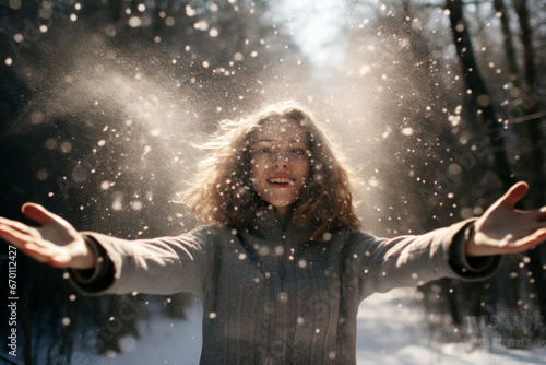 woman throwing snow in the air in the woods at sunny winter day