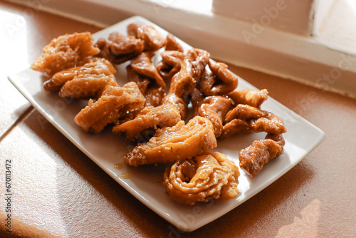 Moroccan chebakias on a white plate in a patio with plants photo