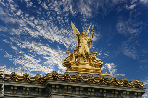 Golden statue of Liberty on the roof of the Opera Garnier (Garnier Palace) against the sky with clouds. Sculpted by Charles Gumery in 1869. Paris, France. UNESCO World Heritage Site