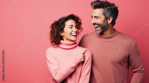 Against a pink background, a young woman and a man smile at each other, symbolizing a happy and close partnership. photo