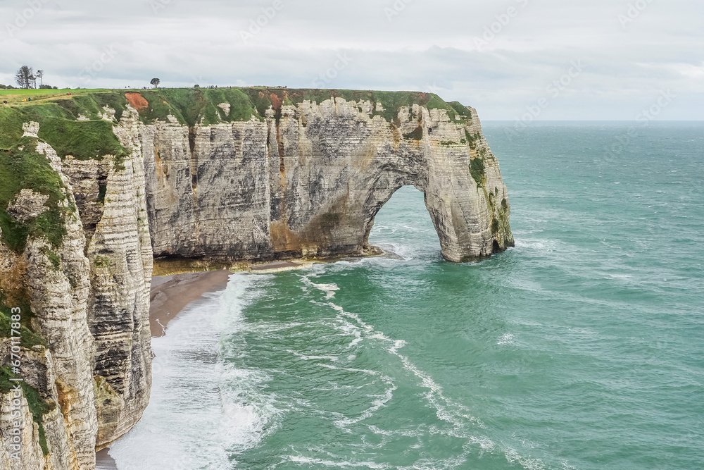 Panoramic view to white Étretat rock La Manneporte. Steep vertical chalk cliff with a natural arch, and beach below, washed by the stormy Atlantic Ocean. Alabaster Coast, Normandy, Northwestern France