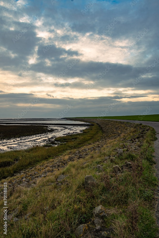 Bei bewölktem Himmel geht es entlang der Deichpromenade Bei bewölktem Himmel geht es entlang der Deichpromenade