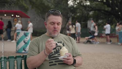 Caucasian White Man eating Soft Serve Pineapple Ice Cream during The Fair photo