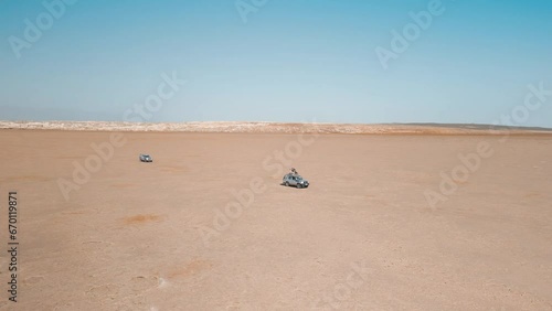 Dallol desert, Danakil Depression, Ethiopia. Fixed aerial drone view of two Land Cruiser SUV travelling in the empty desert. Tourists on roof of vehicle. Famous adventure travel destination.