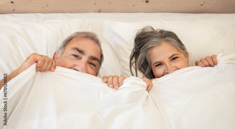 Smiling old caucasian man and lady wakes up in bed, enjoy good morning together, have fun Smiling old caucasian man and lady wakes up in bed, enjoy good morning together, have fun