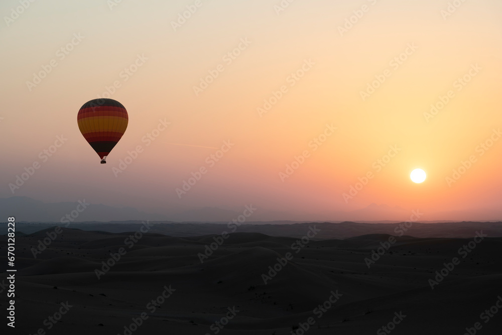 Hot Air Balloon above the desert at sunrise with colourful yellow orange sky and sun. Large copy space for title or other text.