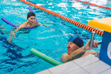senior people in swimming caps using colorful foam pool noodles for support. High quality photo