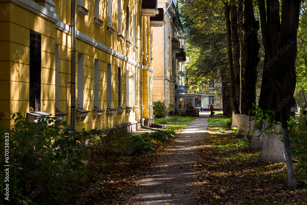 Pedestrian path strewn with fallen leaves on a city street, cityscape Pedestrian path strewn with fallen leaves on a city street, cityscape