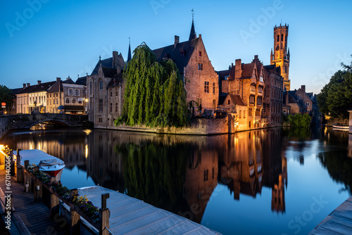 Famous medieval buildings of Brugge with beautiful reflection illuminated during blue hour  photo