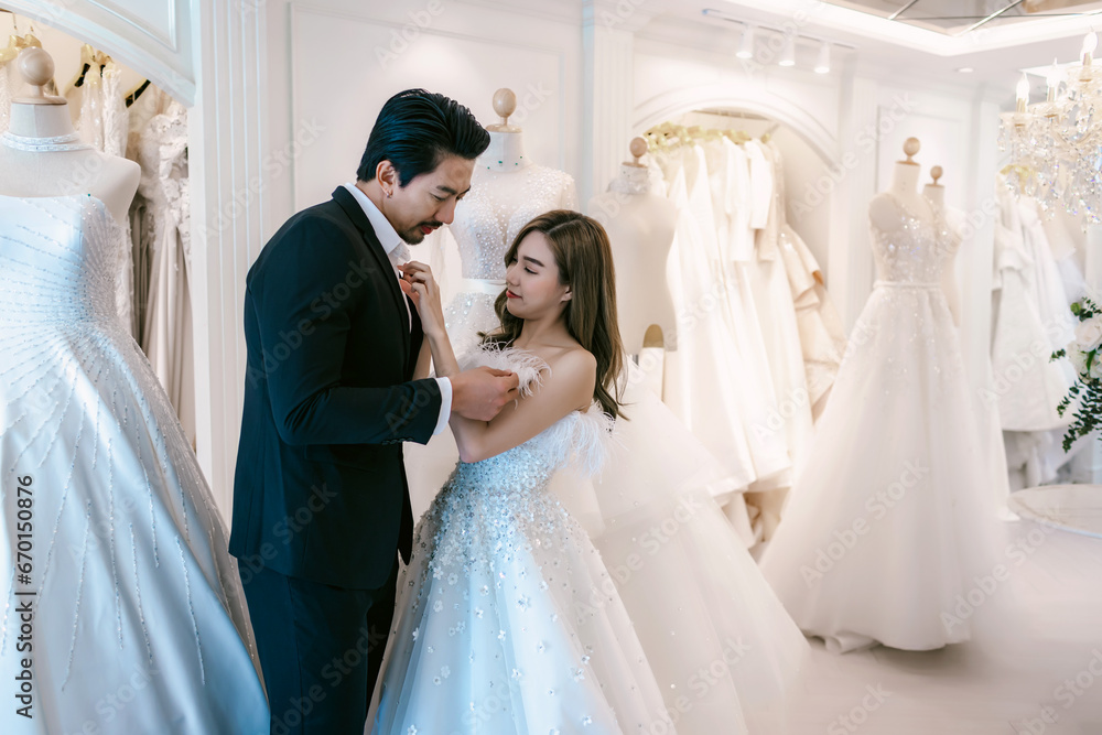 Bride and groom wear dress and try to fitting in modern wedding studio with bridal store owner Bride and groom wear dress and try to fitting in modern wedding studio with bridal store owner