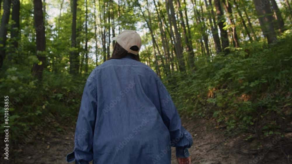 Woman walking in the forest on summer sunny day back view follow shot. Female wonder in the park. A beautiful view of park, tourist hiking Woman walking in the forest on summer sunny day back view follow shot. Female wonder in the park. A beautiful view of park, tourist hiking