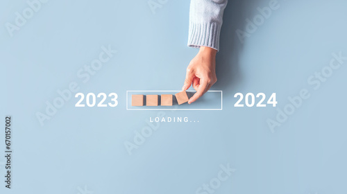 Obraz na plátně Loading new year 2023 to 2024 with hand putting wood cube in progress bar