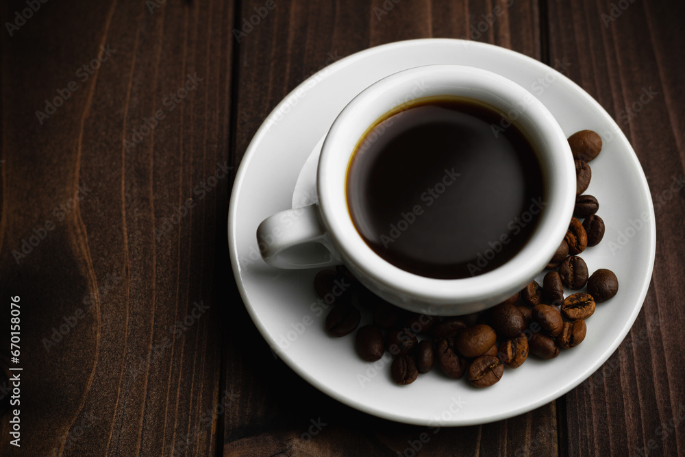 White Cup Of Hot Coffee On Old Weathered Wooden Dark Table With Beans of Coffee.